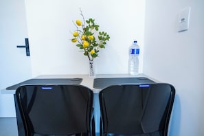 Un salón de conferencias con dos sillas, una botella de agua y un jarrón con flores amarillas.