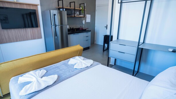 Habitación de hotel con cama, escritorio, refrigerador, microondas y televisión.