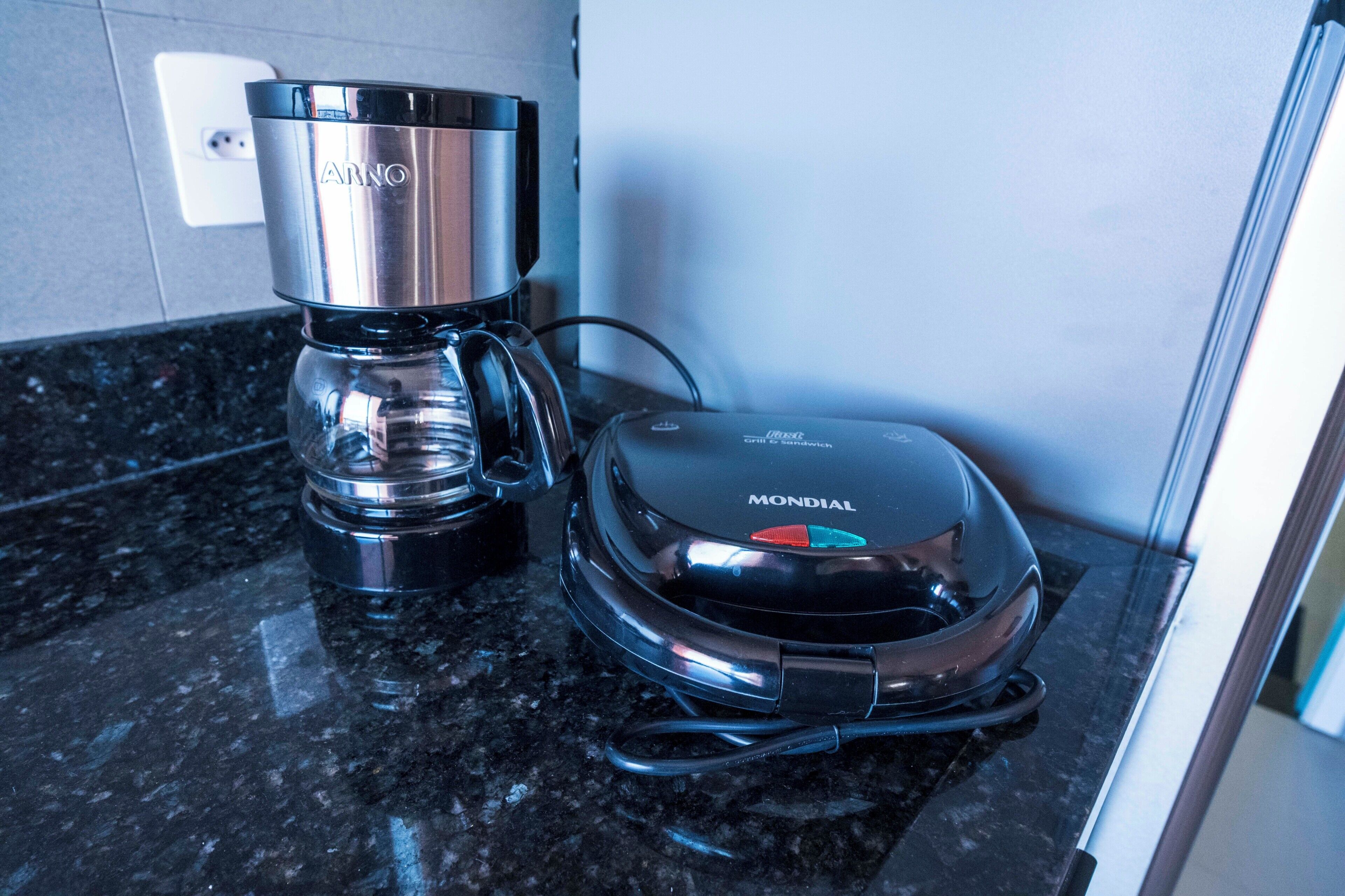 Una cafetera y una parrilla portátil sobre una encimera de cocina.
