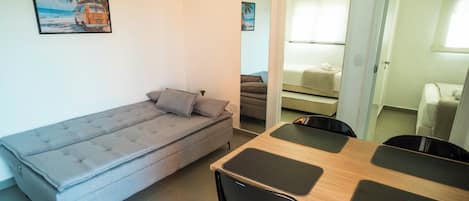 A compact living space with a sofa, a dining table with chairs, and a small kitchenette area.