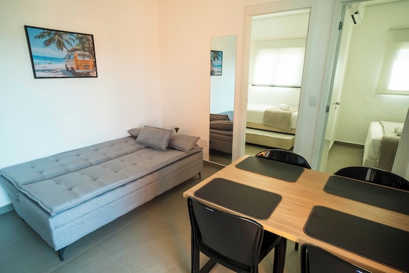 A compact living space with a sofa, a dining table with chairs, and a small kitchenette area. - Vista Cecap (Guarulhos)