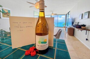 Une bouteille de vin avec une étiquette, une carte avec un message et une vue sur l’océan.