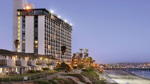 Ein Hochhaus-Hotel mit mehreren Etagen, Blick auf den Strand und einer gut beleuchteten Fassade.