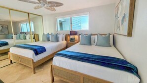 Ein Hotelzimmer mit zwei Betten, einem Deckenventilator, einem großen Spiegel und einem Fenster mit Blick.
