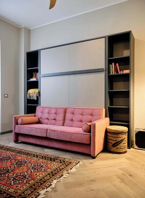 A modern living room with a pink sofa, a patterned rug, and a bookshelf. - Charming Apartment in Milan (Milano)