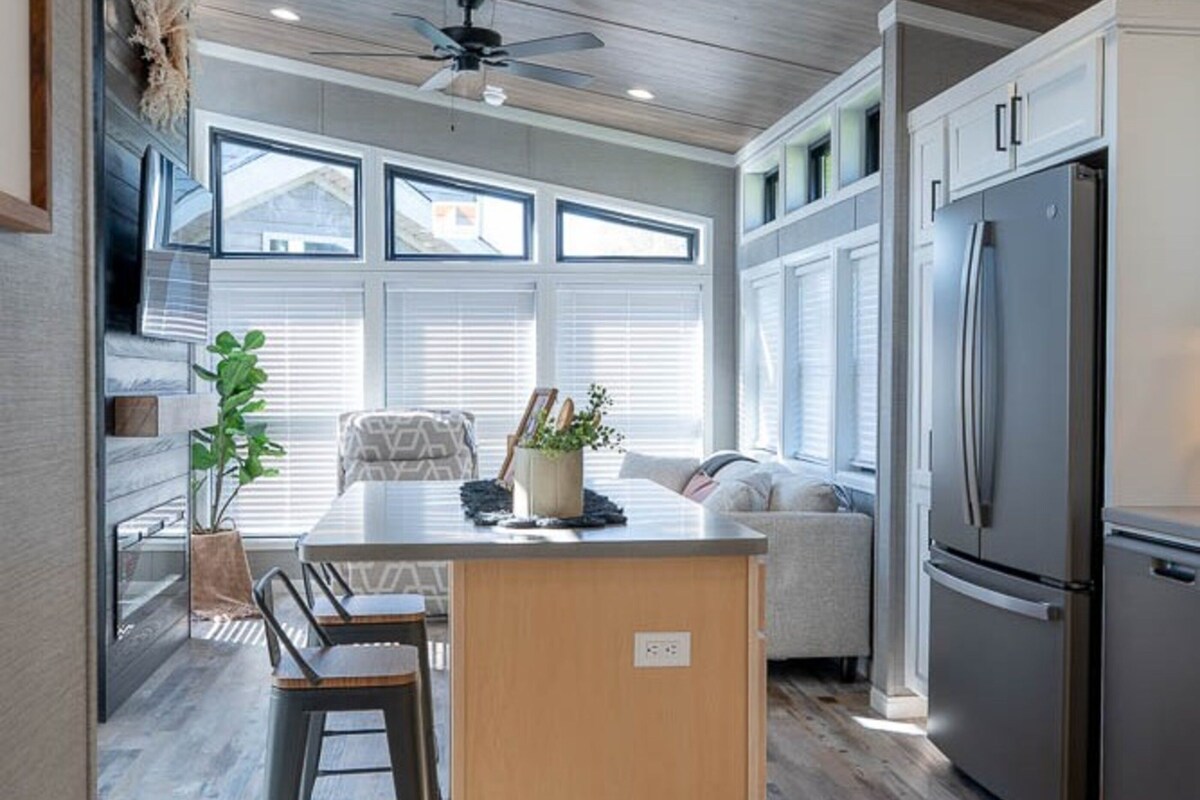 A modern kitchen with a central island, built-in appliances, and large windows.