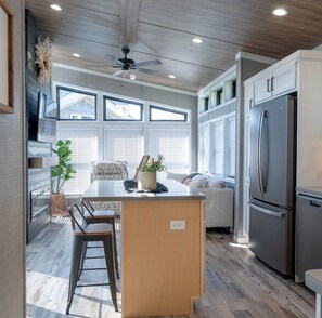 Una cocina moderna con una isla central, electrodomésticos integrados y ventanas amplias.