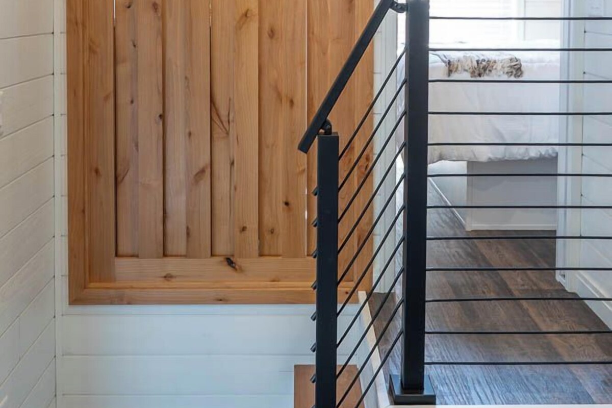 A wooden door with a black metal railing in a hallway.