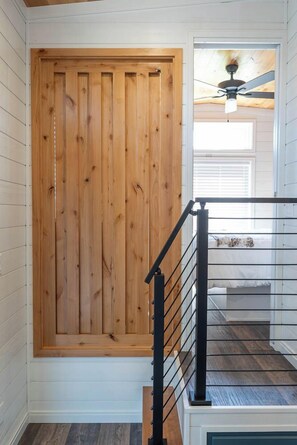 A wooden door with a black metal railing in a hallway. - Frieden Saugatuck (Saugatuck)