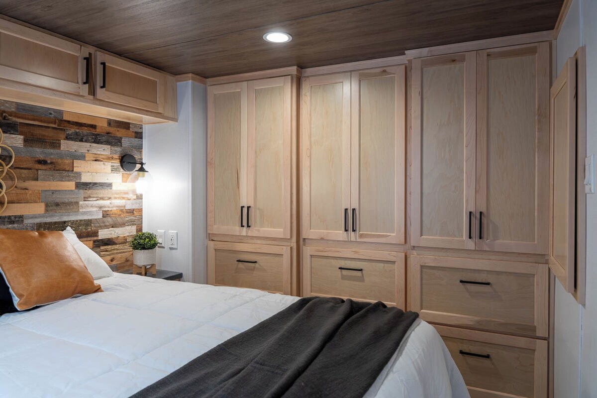 A bedroom with a bed, wooden wardrobe, and a wall with a wooden plank design.