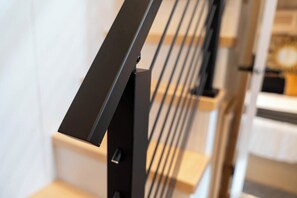 A modern staircase with a black handrail and a metal railing.