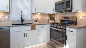A modern kitchen with white cabinetry, a stainless steel stove, and a microwave. - Frieden Saugatuck (Saugatuck)