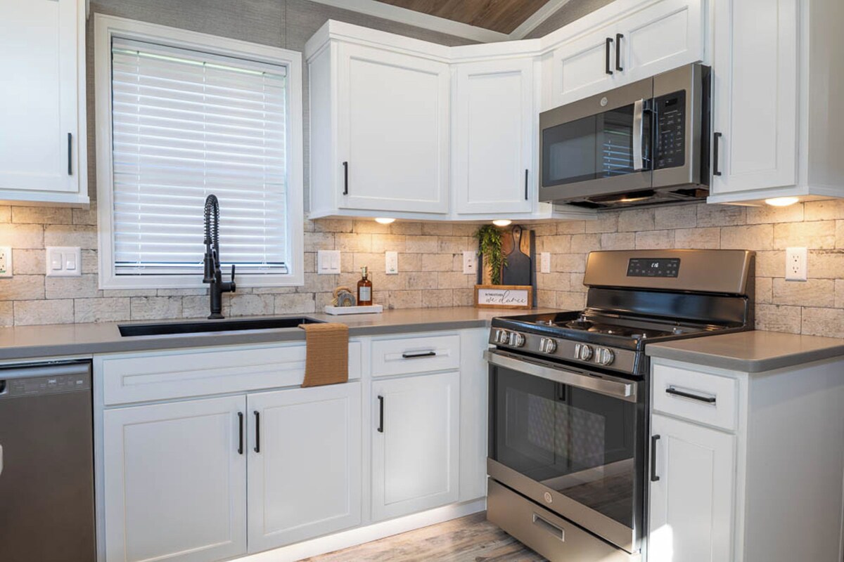 A modern kitchen with white cabinetry, a stainless steel stove, and a microwave.