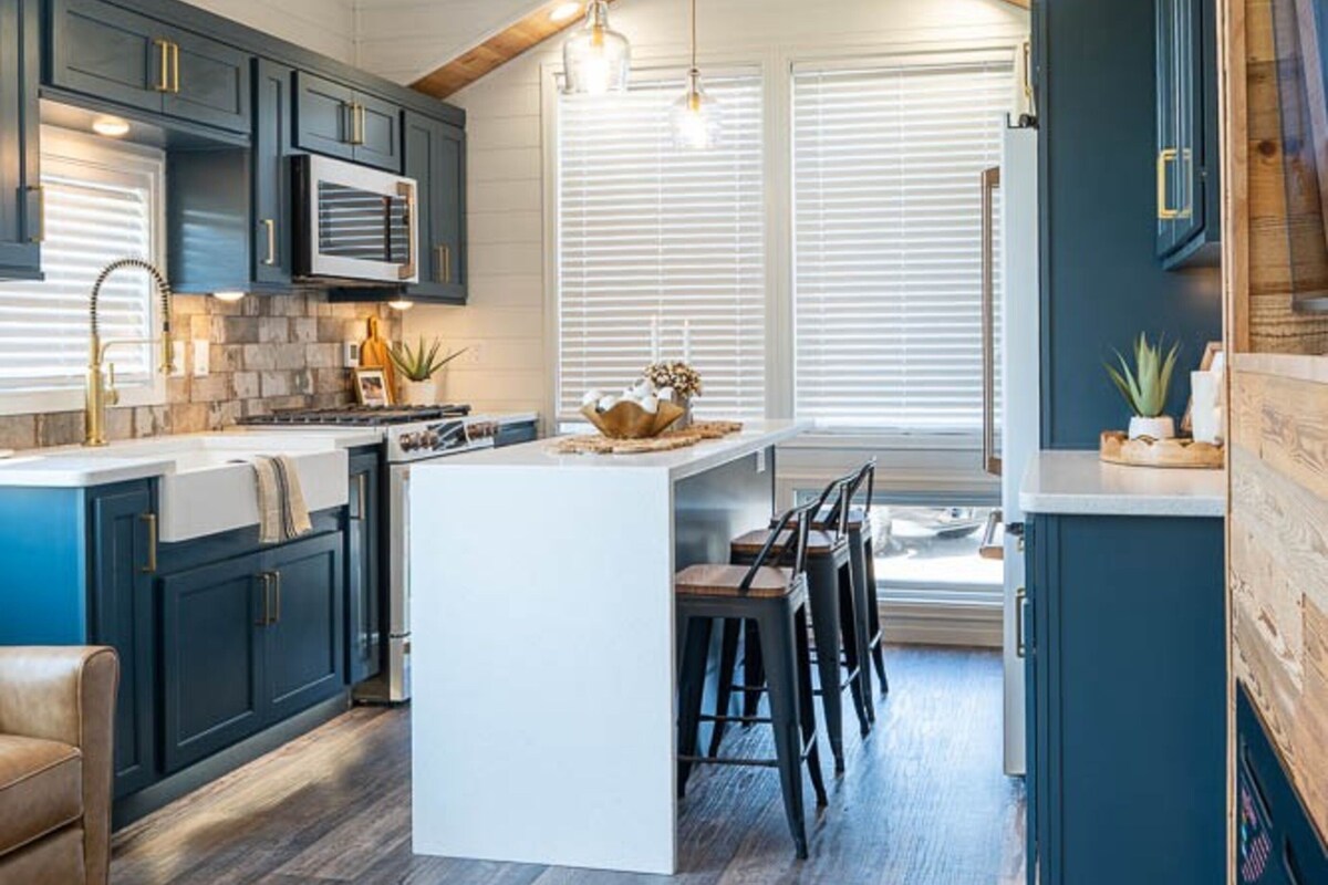 A modern kitchen with dark cabinetry, a central island, and pendant lighting.