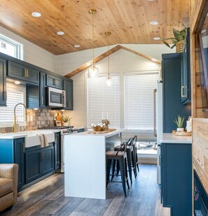 A modern kitchen with dark cabinetry, a central island, and pendant lighting.