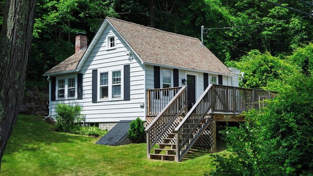 A two-story house with a wooden deck and a ramp leading to the entrance. - Creekside Cabin by Avantstay Creek Swims + Trout Fishing Firepit Deck Views Near Hunter Mtn (Jewett)