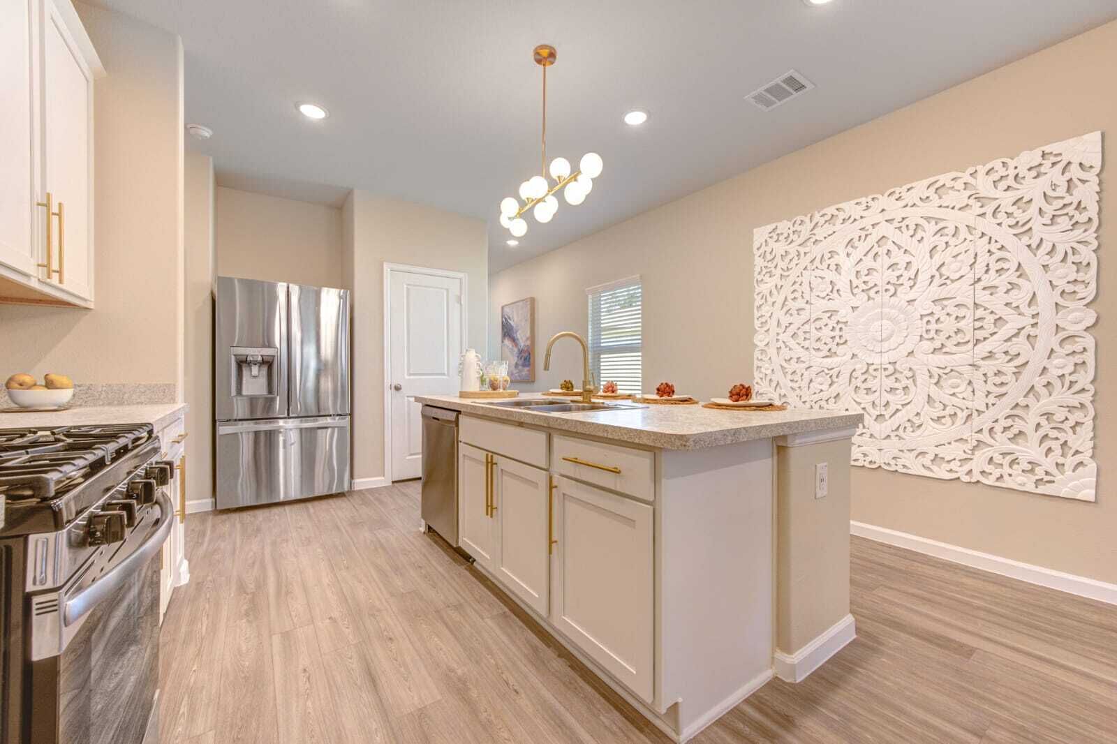 A modern kitchen with stainless steel appliances, a central island, and a decorative wall panel.