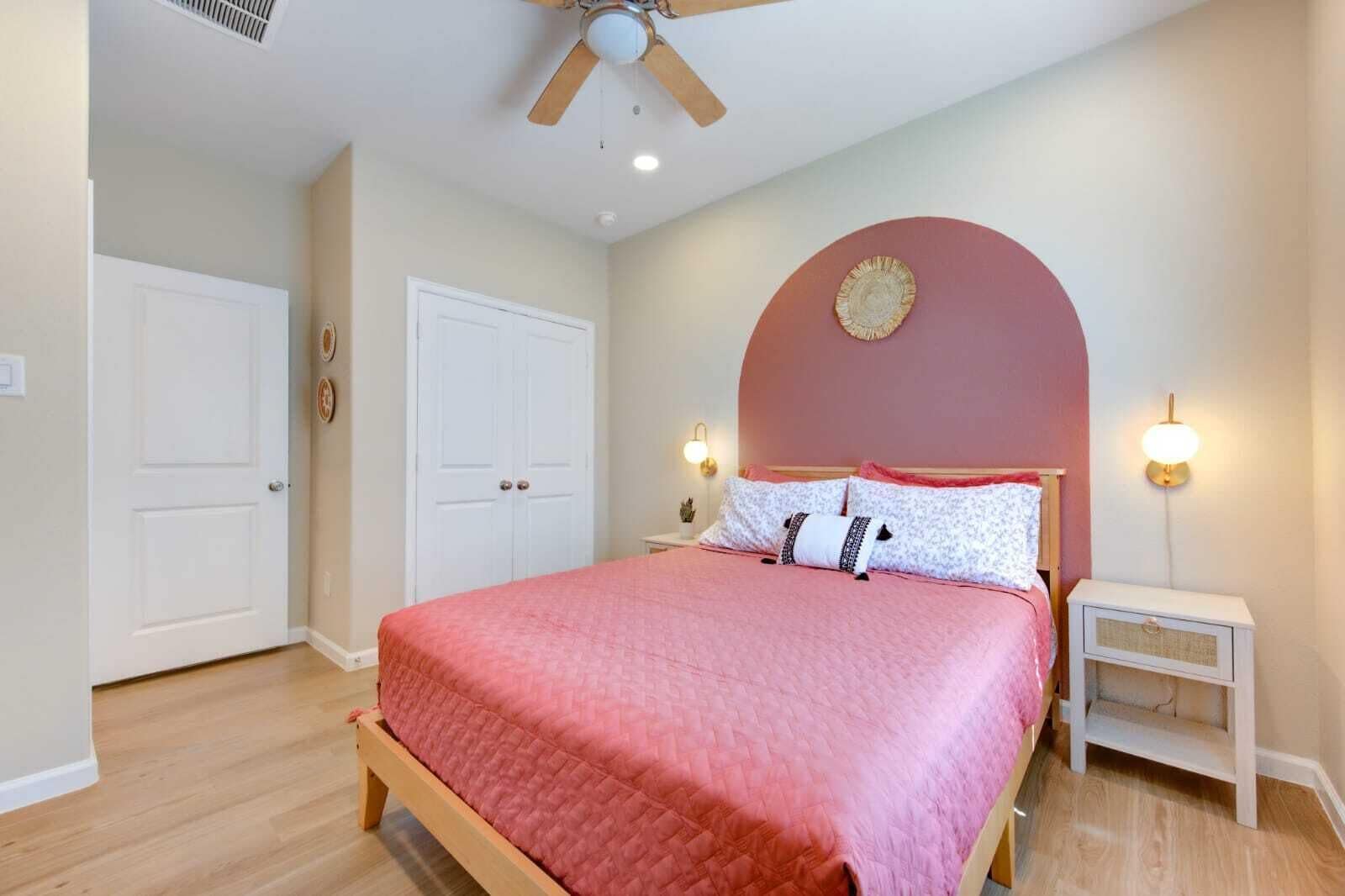 A bedroom with a bed, a ceiling fan, two bedside tables, and a nightstand.