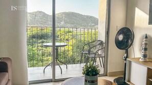 Ein Balkon mit Tisch, Stühlen, einem Ventilator und einem Blumentopf.