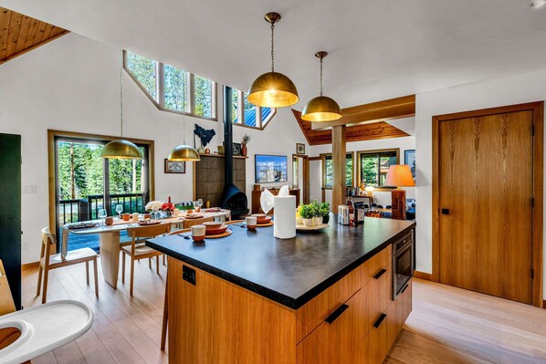 Une cuisine moderne dotée d’un îlot central, de meubles en bois et de luminaires suspendus.