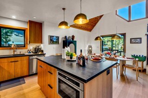Una cocina moderna con una isla central, electrodomésticos de acero inoxidable e iluminación colgante.