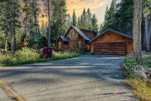 Eine Holzhütte mit Garage und überdachter Veranda, umgeben von Wald.