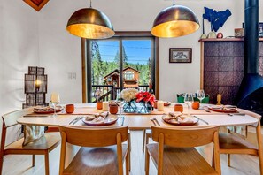 Un comedor con una gran mesa de madera dispuesta para cuatro personas, rodeada de sillas de madera.