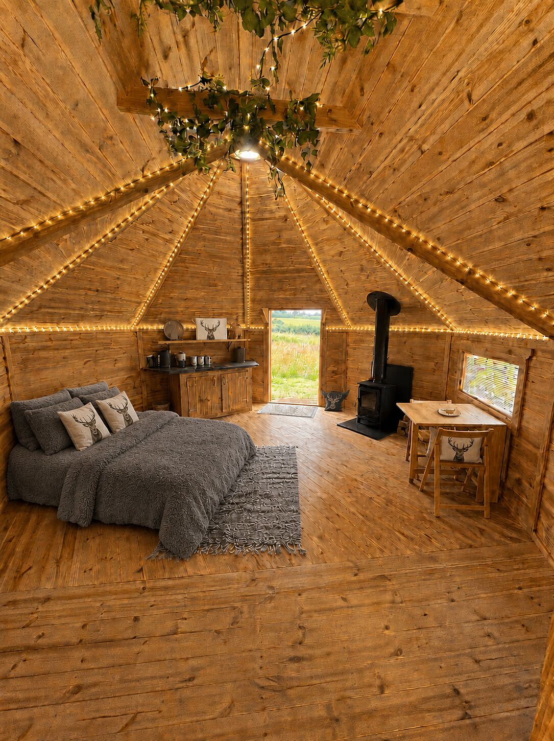 A cozy, wooden interior with a bed, a table, and a fireplace.