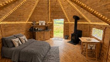 A cozy, wooden interior with a bed, a table, and a fireplace.