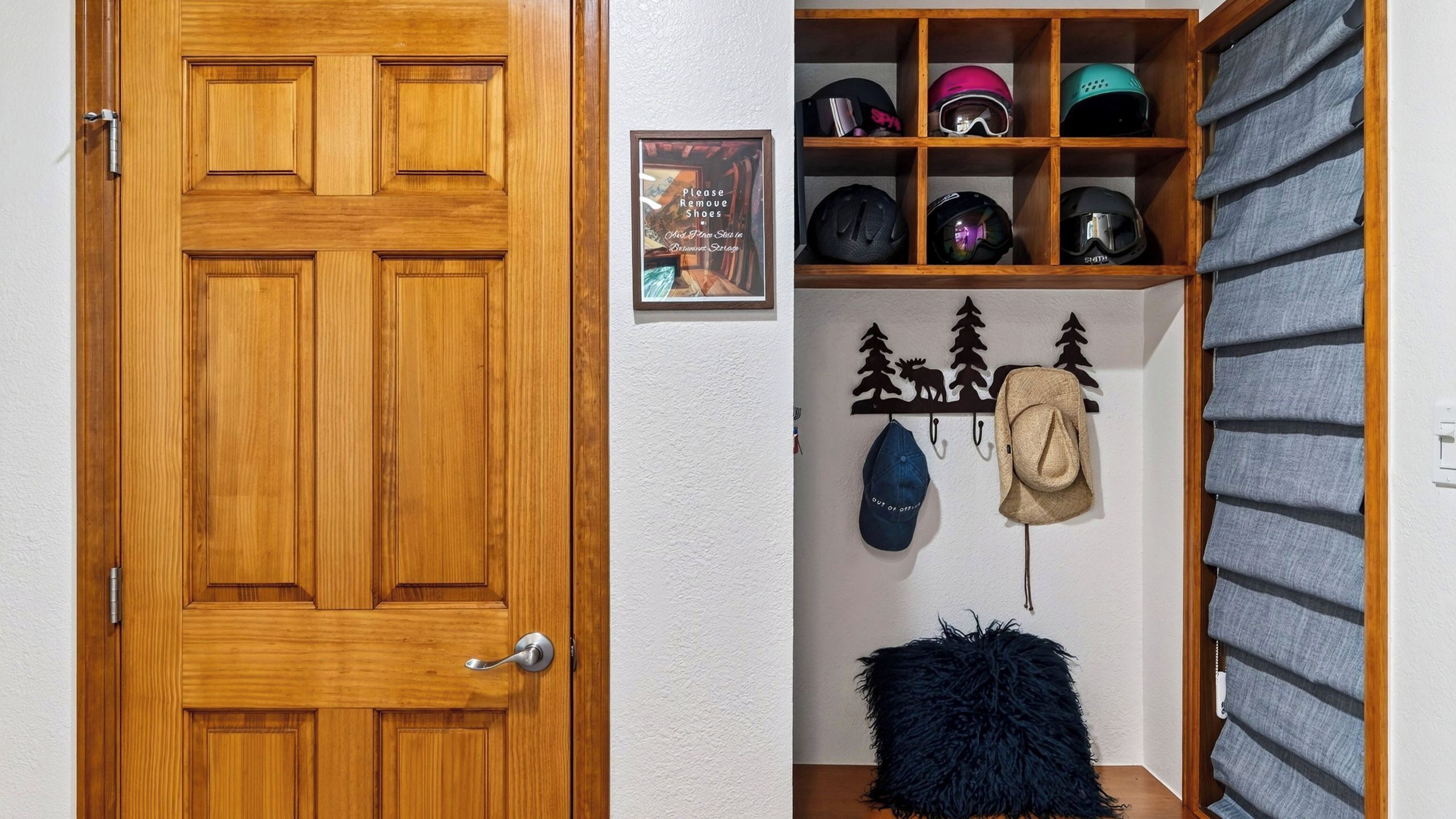 Uma porta de madeira, uma prateleira com capacetes e um porta-chapéus fixado na parede.