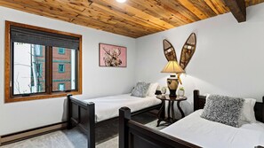 A room with a bed, a small table with a lamp, and a window with blinds. - Falls & Firs by Avantstay Mtn Views + Balcony Trailheads + Ski Bus (Vail)