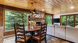 A wooden interior with a stone fireplace, a dining table with chairs, and a sofa. - Falls & Firs by Avantstay Mtn Views + Balcony Trailheads + Ski Bus (Vail)