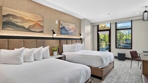 Ein Hotelzimmer mit zwei Betten, einem Schreibtisch und großen Fenstern mit Blick ins Freie.
