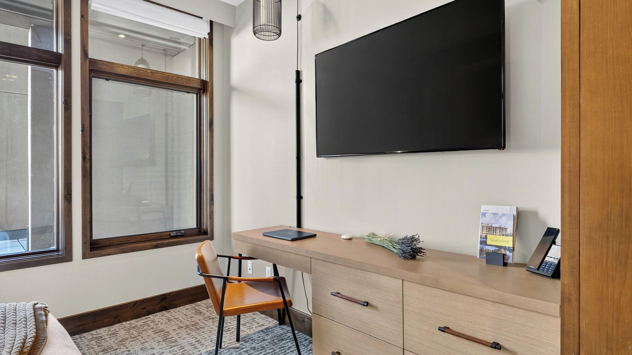 Une chambre moderne équipée d’un bureau, d’une chaise et d’un téléviseur à écran plat fixé au mur.