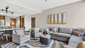 Un salon moderne comprenant un canapé, des fauteuils, une table basse et un coin repas avec une table et des chaises.