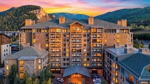 Un hôtel à plusieurs étages doté d’une cour intérieure, entouré d’un paysage montagneux.
