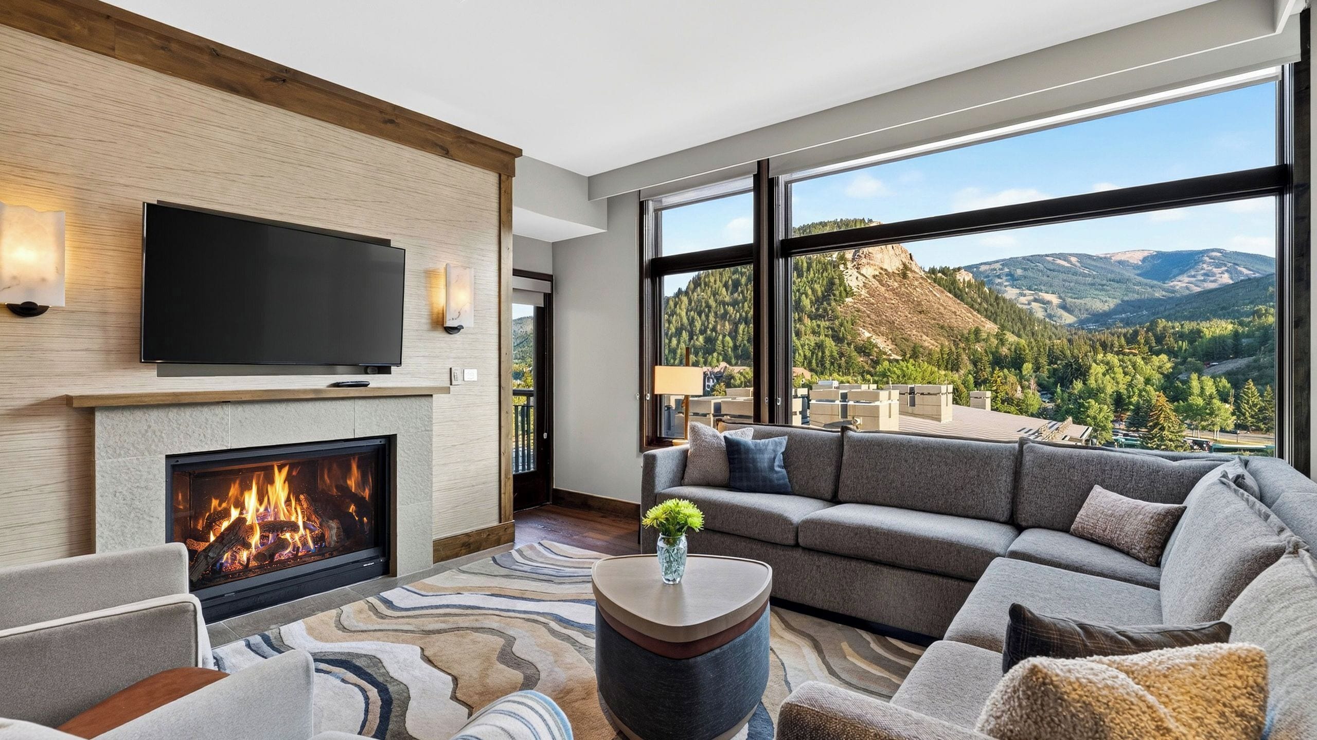 A modern living room with a fireplace, a large flat-screen TV, and a sofa.