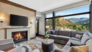 A modern living room with a fireplace, a large flat-screen TV, and a sofa.
