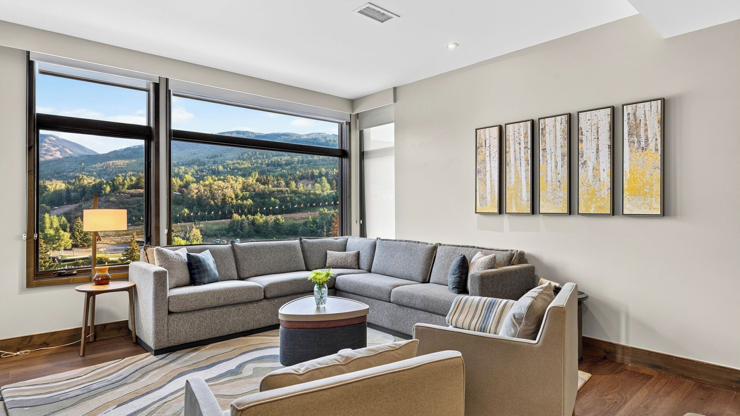 A modern living room with a large window, a sectional sofa, a coffee table, and a rug.