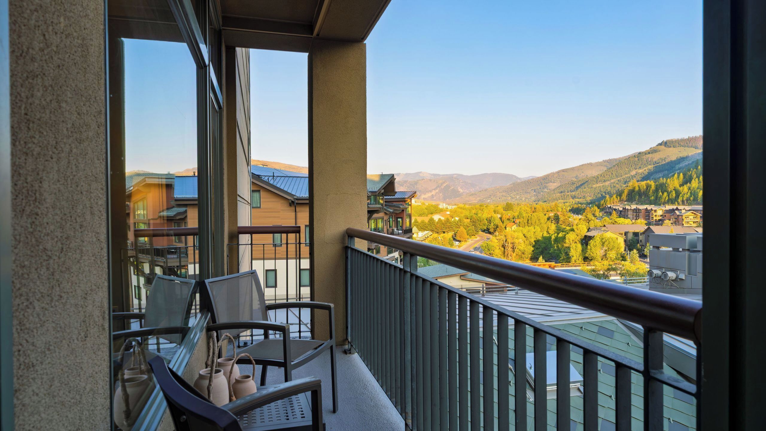 A balcony with a view of a mountainous landscape and autumn-colored trees.