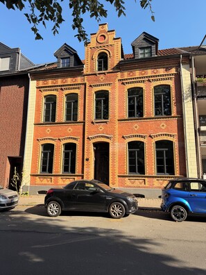 A two-story brick building with a prominent tower and arched windows. - Completely renovated apartment in an older building in the heart of Ratingen with excellent transportation access (Ratingen)