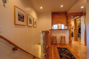 A wooden staircase with a handrail, a wooden wall with framed pictures, and a patterned rug on the floor. - Tahoe Village Summit Escape (Stateline)