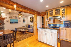 A cozy living room with a sofa, coffee table, and a dining area with a table and chairs. - Tahoe Village Summit Escape (Stateline)