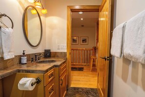 Une salle de bain avec un grand miroir, un lavabo et un porte-rouleau de papier toilette.