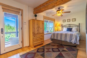 A bedroom with a bed, a ceiling fan, a window, a wooden cabinet, and a door leading outside. - Tahoe Village Condo | Walk to Heavenly Stagecoach (Stateline)