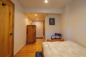 A bedroom with a wooden wardrobe, a bed with a patterned duvet, a chair, and a painting on the wall. - Tahoe Village Summit Escape (Stateline)