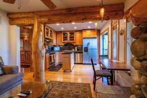 A rustic kitchen with wooden beams, a refrigerator, a microwave, and a dining area with a table and chairs. - Tahoe Village Condo | Walk to Heavenly Stagecoach (Stateline)