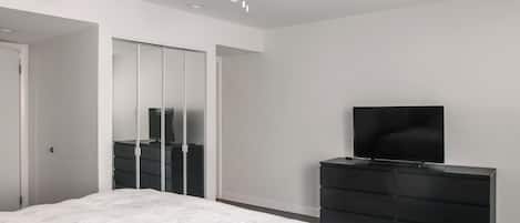 A bedroom with a bed, a dresser, a television, and a ceiling fan.