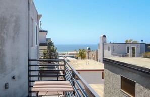 Un balcón con vista al mar, un edificio con el número 6 y un cielo despejado.