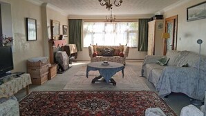 A living room with a round coffee table, sofas, a television, and a chandelier. - The Hollies (Walmer)